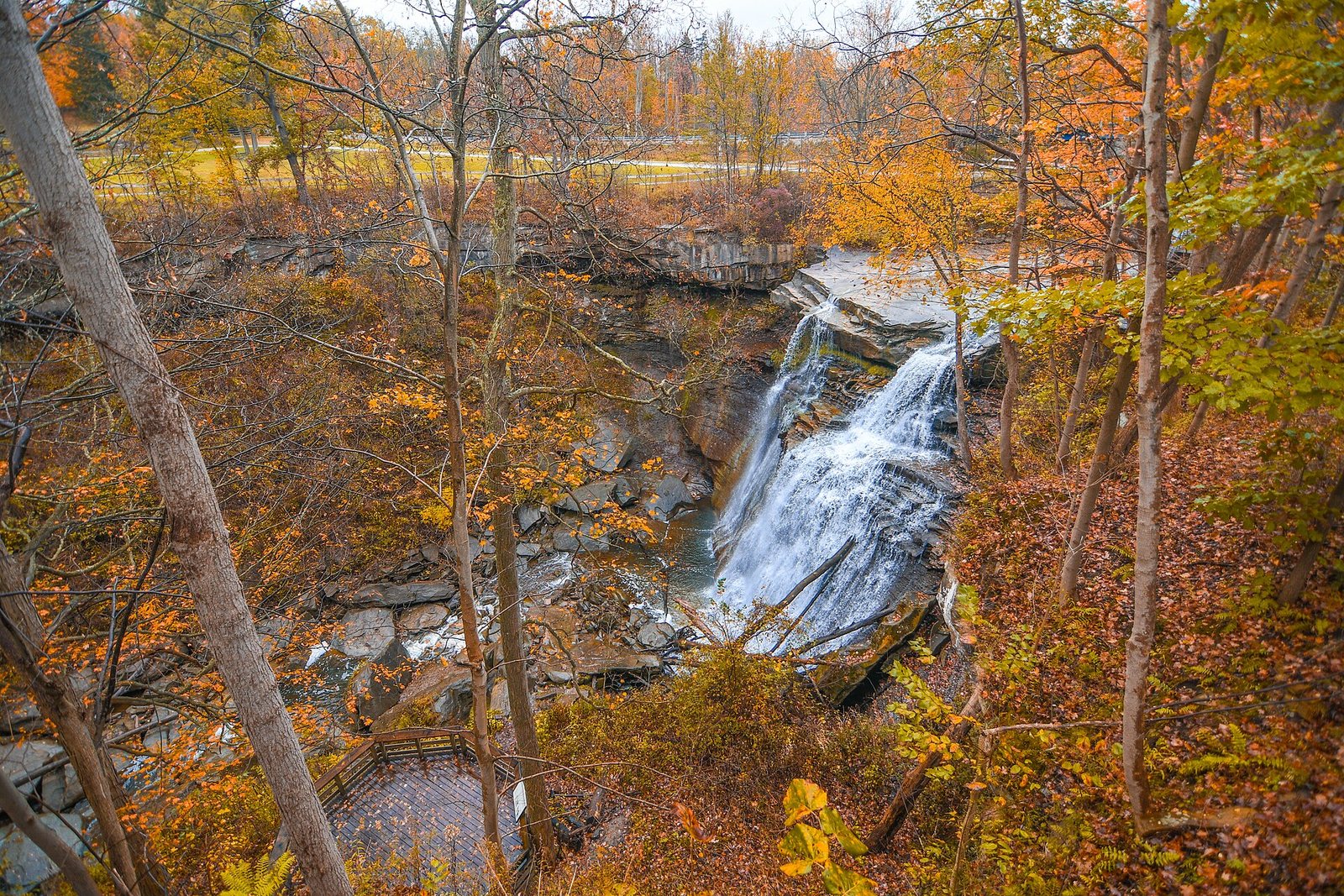 Brandywine Falls dropping into a gorge among orange and gold trees, with a viewing platform below.