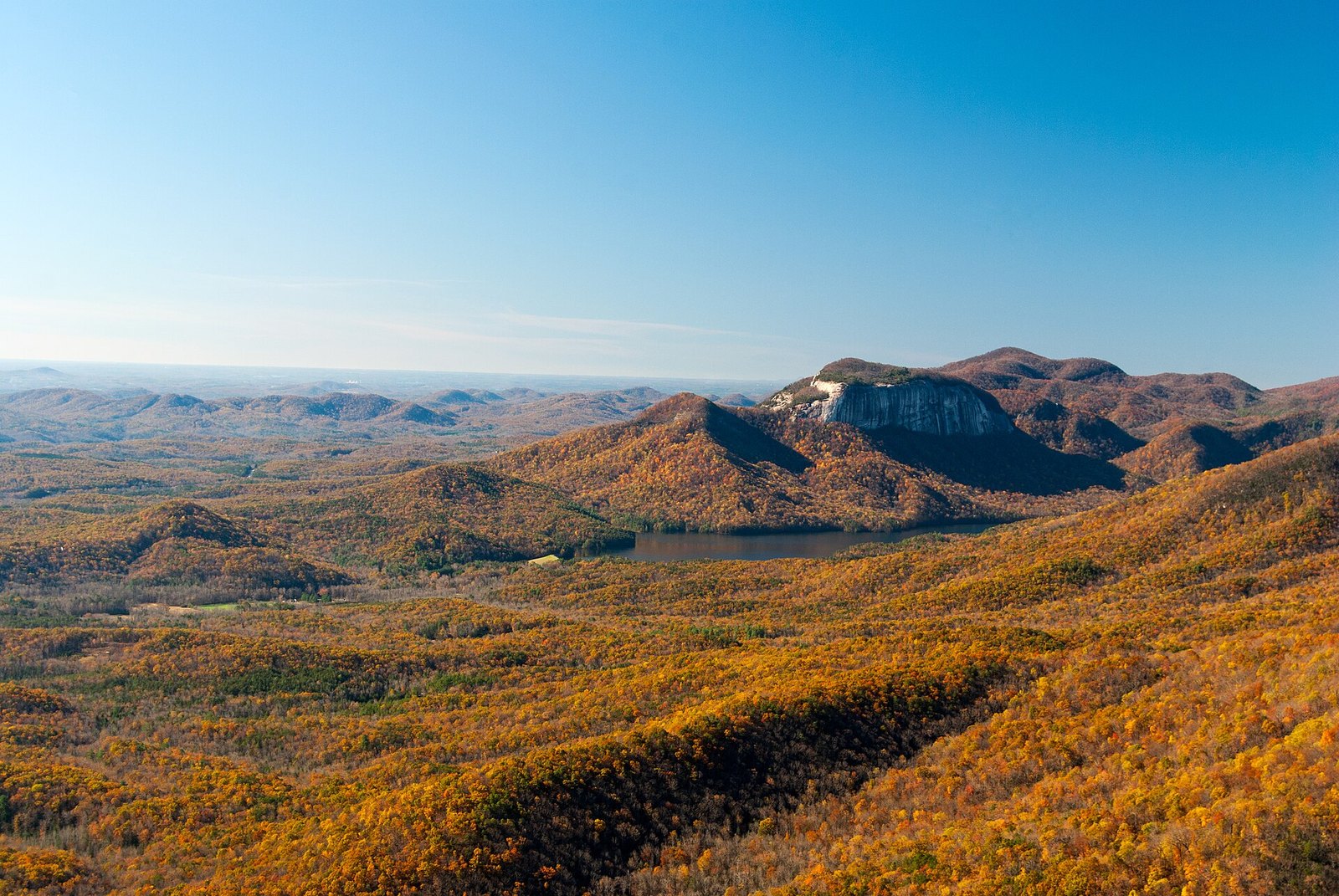 The pale granite dome of Table Rock in the distance with a lake at its foot, above hillsides of gold and orange trees.