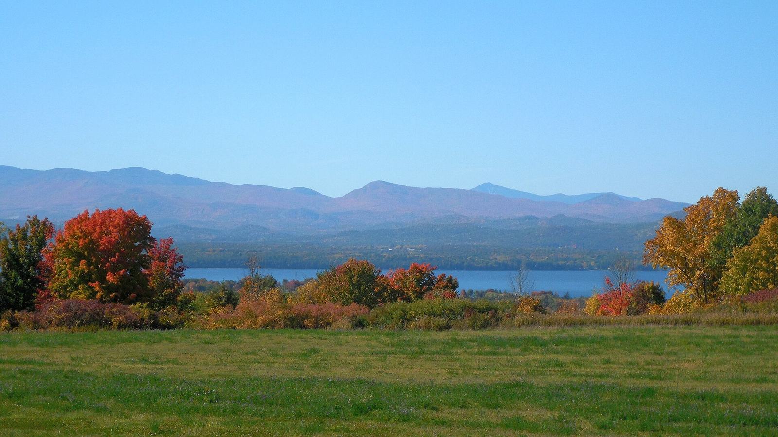 Lake Champlain and the Adirondacks from a Charlotte meadow, with red and orange maples along the shore.